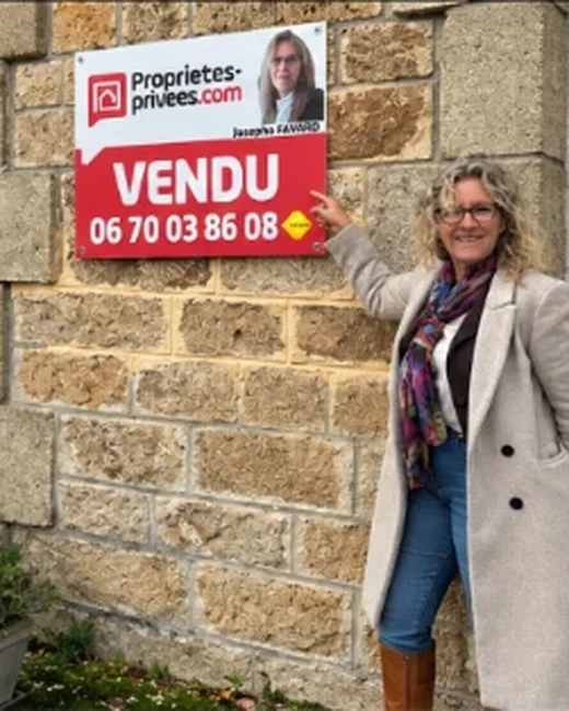 Josepha Favard devant le panneau VENDU d’une maison en granit clair