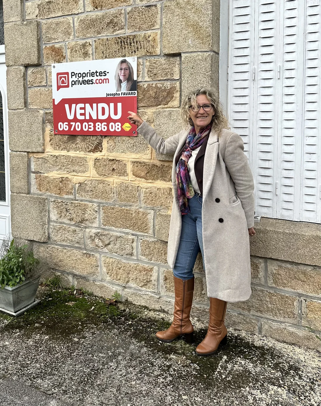 Josepha Favard devant le panneau VENDU d’une maison en granit du secteur de Treignac
